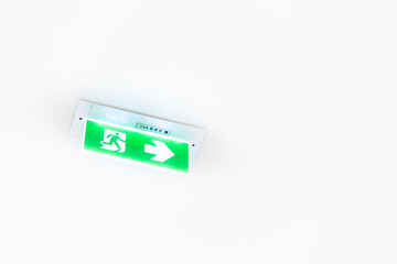 White neon sign depicting a fire exit with green background hangs from the ceiling.
