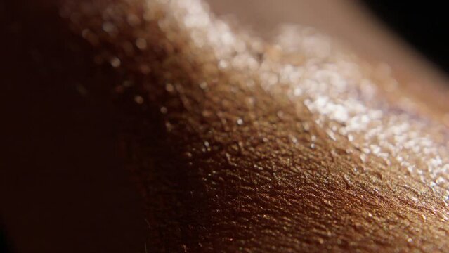 super closeup of a finger applying golden liquid makeup on human skin in slow motion