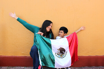 Latin Mexican mom and son show the flag of Mexico very proud of their culture and tradition, to...