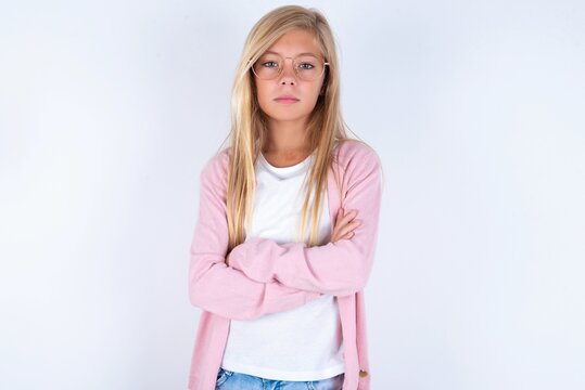 Picture of angry caucasian blonde little girl wearing pink jacket and glasses over white background looking camera.