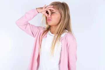 Foto op Canvas Displeased caucasian blonde little girl wearing pink jacket and glasses over white background plugs nose as smells something stink and unpleasant, feels aversion, hates disgusting scent. © Jihan