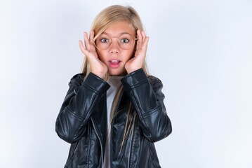 beautiful caucasian blonde little girl wearing biker jacket and glasses over white background Pleasant looking cheerful, Happy reaction