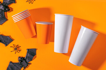 Halloween party background with Paper cup with spiders, bats. Disposable cup made of recycled paper orange colors. Pattern for outumn october holiday all saints day celebration