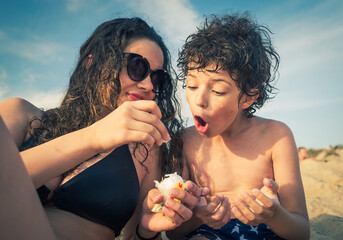 Older sister and little brother brunettes eat cotton candy at sea