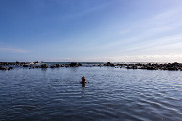 Tourist woman swimming in the lagoon of beach Playa Charco del Conde in Valle Gran Rey, La Gomera, Canary Islands, Spain, Europe. Panoramic sea view of beautiful shoreline of Atlantic Ocean. Vacation
