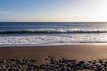 Scenic view on beach Playa Valle Gran Rey during sunset seen from Promenade de Playa de La Calera in Valle Gran Rey on La Gomera, Canary Islands, Spain, Europe. Dark volcanic sand beach with pebbles