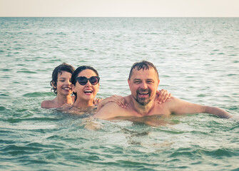 Dad, daughter and son bathe swimming in the sea and having fun together. Paternity concept