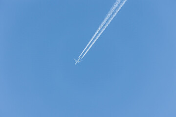 A plane with white contrails flies in the blue sky over Augsburg in Bavaria