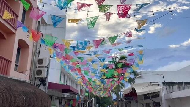 colorful papel picado hanging over a street in Playa Del Carmen Mexico