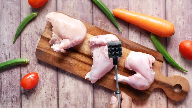 precessing raw chicken breast on a chopping board 