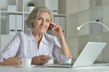 Elderly woman in headphones take online course on computer at home.