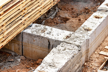 Reinforced concrete foundation of a modern monolithic residential building. Prepared formwork with reinforcing mesh for pouring concrete. Dirt and clay at the construction site.