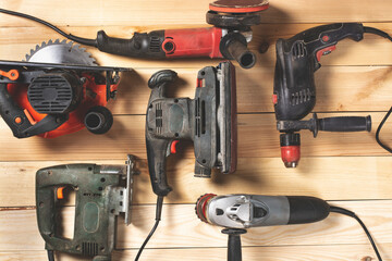 Construction carpentry tools. Electric corded circular saw, jigsaw, drill on wooden background