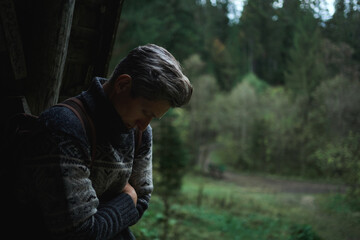 Sad unhappy man looking down and feeling cold during hiking in forest. Gloomy silhouette portrait