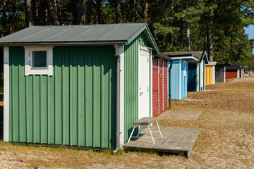 Fototapeta na wymiar Little cozy tiny wooden multicolored houses on a beach in Sweden. Sunny summer day.