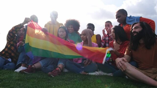 Group of friends of different ethnicities placing the lgtbi+ flag well to fight for rights and pride