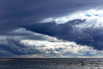 Fototapeta premium Funnel - shaped horizontal clouds on stormy dark cloudy sky over Baltic sea just before a sea storm in Riga, Latvia. Nature environment concept. Weather Forecast Concept.