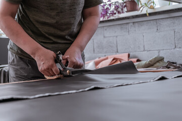 A cutter cuts fabric with scissors in a sewing workshop