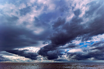 Obraz premium Dramatic stormy dark cloudy sky over Baltic sea just before a sea storm in Riga, Latvia. Nature environment concept.