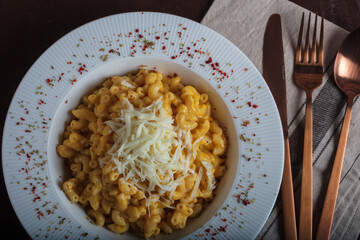 Mac and cheese, american style macaroni pasta with cheesy sauce on dark rustic table, top view....