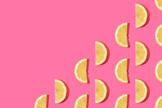 Citrus pattern made with fresh lemon slices on vibrant pink background. Minimal juicy exotic fruits concept. Healthy food fun composition.
