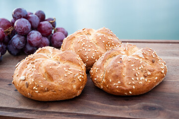 Three buns with sesame and grape on a .cutting board above the river