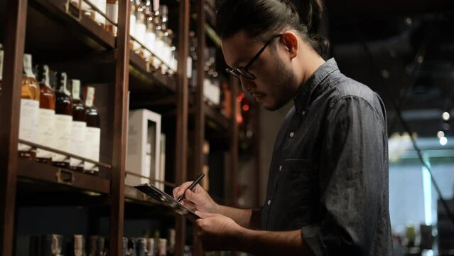 Night club concept of 4k Resolution. The bartender is checking the merchandise in the store. A group of specialized clubs that sell alcoholic beverages.