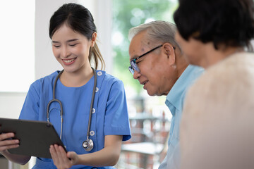 Asian woman doctor work in nursing home with digital tablet consults service to patient explains health care symptoms and help elderly family, Concept of elderly care, health care and insurance.