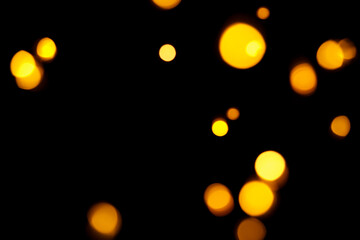 Gold bokeh on dark background. Defocused golden lights. New Year, Christmas background, abstract texture