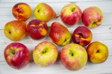 Bright pink apples, pears and nectarines are placed on a table made of gray boards. Vegetables and fruits. Useful products.