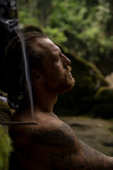 Fototapeta na wymiar A man in a sacred temple with a waterfall in Bali, incense, Bali traditions, places of power.