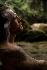 Fototapeta na wymiar A man in a sacred temple with a waterfall in Bali, incense, Bali traditions, places of power.