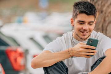 young man with mobile phone sitting on the street