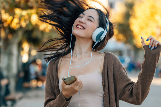 girl with headphones and mobile phone dancing on the street in autumn