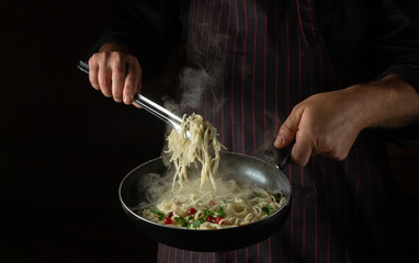 Cooking spaghetti with spices and seasonings in a pan by the hands of an experienced chef. Recipe or menu for a restaurant or cafe on a black background