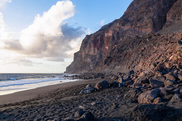 Scenic view during sunset on the volcanic sand beach Playa del Ingles in Valle Gran Rey, La Gomera, Canary Islands, Spain, Europe. Massive cliffs of the La Mercia range. Calm atmosphere at the seaside
