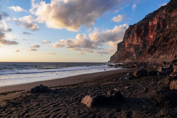 Scenic view during sunset on the volcanic sand beach Playa del Ingles in Valle Gran Rey, La Gomera, Canary Islands, Spain, Europe. Massive cliffs of the La Mercia range. Close up on Rock formation