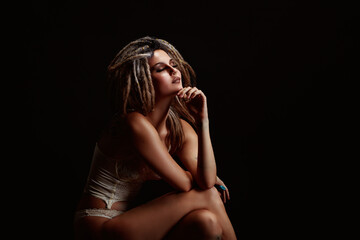 Portrait of seated pensive young woman wearing dreadlocks with hand under chin