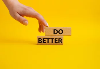 Fotobehang Do better symbol. Wooden blocks with words Do better. Beautiful yellow background. Businessman hand. Business and Do better concept. Copy space. © Natallia