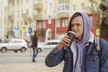 Hipster man with dreadlocks drinking hot coffee on street. Young male in warm clothes drinking hot beverage