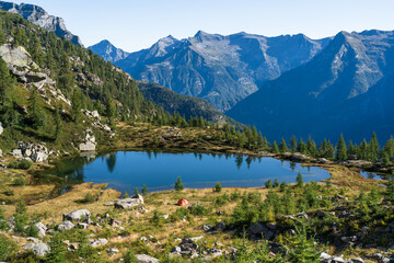 Lake and a red tent in the mountains of Ticino on a summers mornig.
