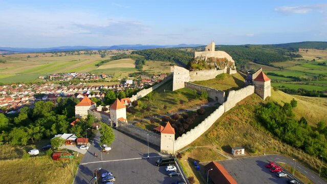 Aerial drone view of Rupea Fortress at sunset, Romania. Citadel located on a cliff, tourists, town, greenery