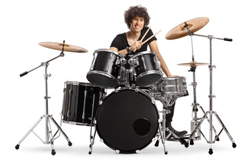 Smiling young male drummer holding drumsticks and sitting with a drum set