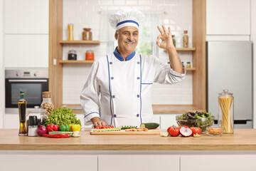 Chef posing behing a kitchen counter with vegetables and gesturing great