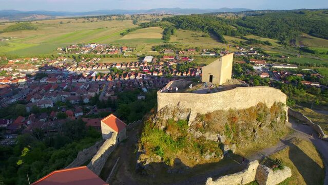 Aerial drone view of Rupea Fortress at sunset, Romania. Citadel located on a cliff, tourists, town, greenery