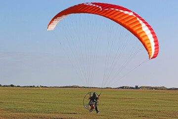 Paramotor pilot taking off from a field