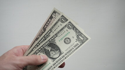 Three American one dollar bills in a man's hand