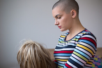 Sick bald woman cancer patient sitting on hospital bed and holding wig before going home