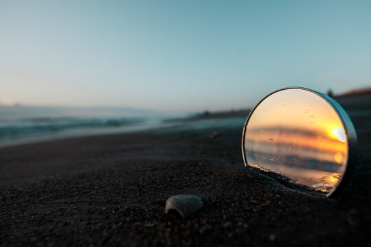 Mirror stuck in the sand during sunrise at the beach 