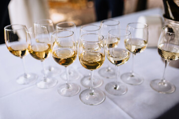 A lot, a row of glass glasses with champagne stands on the table.